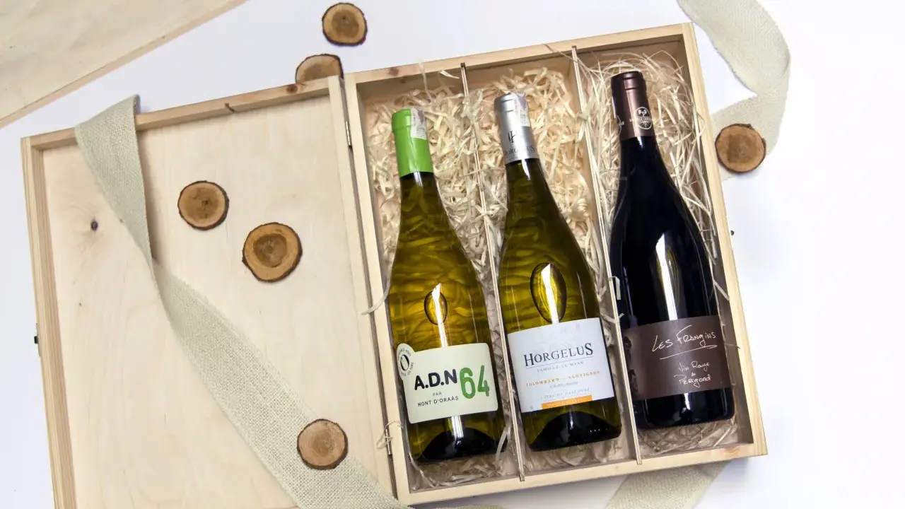 Eleganckie wino w skrzynce na prezent, idealne na wyjątkową okazję. Drewniana skrzynka z trzema butelkami wina, ozdobiona jutową wstążką i drewnianymi krążkami.
