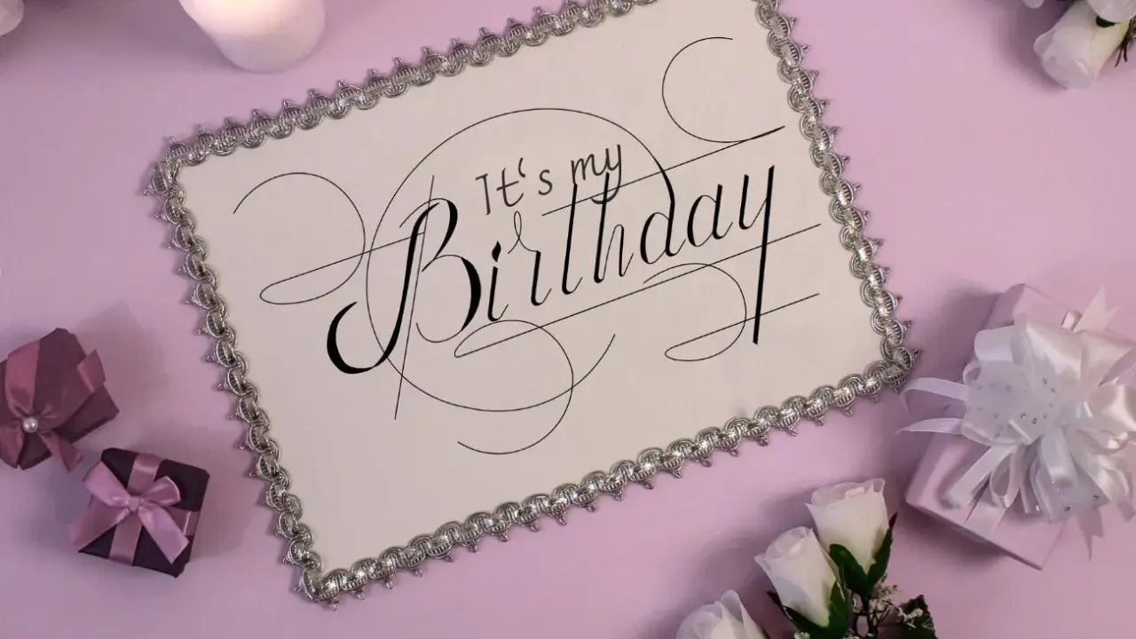 Eleganckie zaproszenie na urodziny w stylu savoir vivre. Biała kartka z ozdobnym napisem "It's my Birthday", otoczona prezentami i świecą.