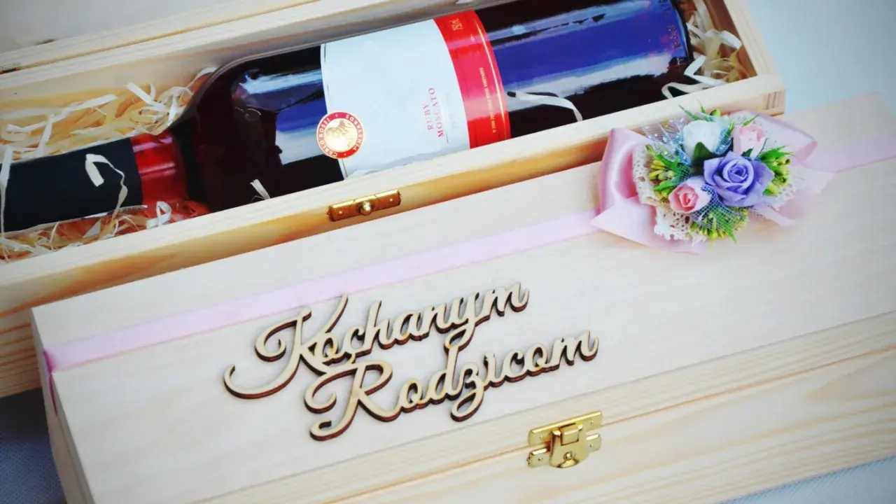 Elegancka skrzynka na wino dla chrzestnych z napisem "Kochanym Rodzicom" i ozdobną kokardką z kwiatami.