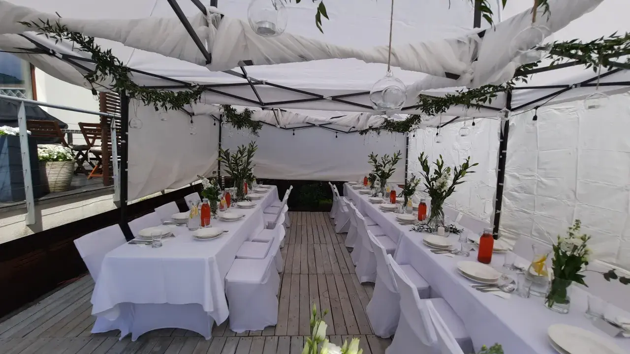 Elegancka komunia w namiocie. Białe obrusy, kwiaty i szklane lampiony tworzą uroczystą atmosferę.