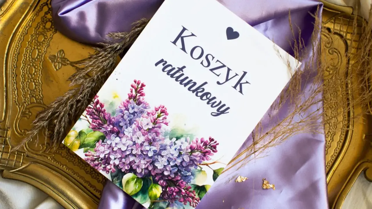 Eleganckie elementy zaproszenia: kartka z napisem "Koszyk ratunkowy", ozdobiona bukietem bzu, na tle fioletowej satyny i złotej ramki.