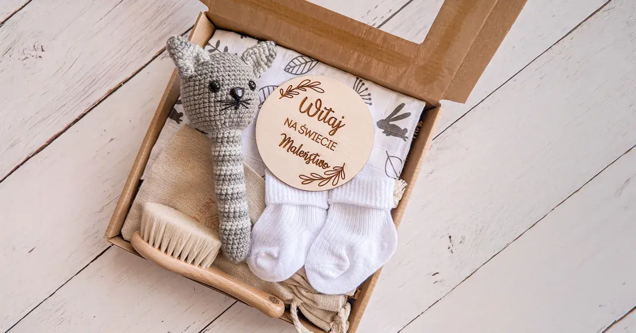 Zestaw na baby shower: szydełkowy kotek, skarpetki, szczotka i tabliczka "Witaj na świecie Maleństwo". Idealny pomysł, ile dać na baby shower.
