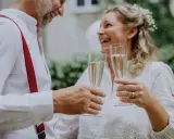 Szczęśliwa para wznosi toast szampanem. To ich piękny ślub po 40. roku życia.