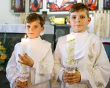 Dwóch chłopców w albach trzyma zapalone świece. Czy do komunii potrzebna jest świeca? Tak, symbolizuje światło Chrystusa.