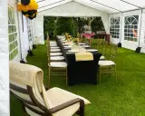 Elegancka komunia w namiocie. Dekoracje stołu z czarnym obrusem i złotym bieżnikiem, balony, słoneczniki.
