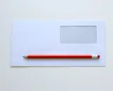 Biała koperta z okienkiem i czerwony ołówek. Proste narzędzia, by dowiedzieć się, jak wypełnić kopertę do wysłania.