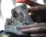 Dłoń trzyma polskie banknoty 10 i 50 zł. Zastanawiasz się, ile pieniędzy na bierzmowanie to odpowiednia kwota?