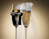 Dwa kieliszki szampana, jeden w stroju pana młodego, drugi z welonem panny młodej. Idealne wino dla pary młodej na toast.
