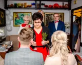 Rodzina udziela błogosławieństwa młodej parze. Kobieta trzyma gałązkę ziół, symbolizującą pomyślność.
