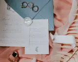 Eleganckie wypisywanie zaproszeń ślubnych z obrączkami i pieczęcią lakową.