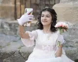 Dziewczynka w sukni komunijnej robi selfie z bukietem kwiatów. To ważny moment, przygotowania do pierwszej komunii świętej krok po kroku.