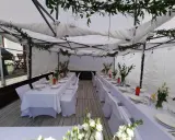 Elegancka komunia w namiocie. Białe obrusy, kwiaty i szklane lampiony tworzą uroczystą atmosferę.
