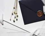 Elegancki papier na zaproszenia ślubne, ciemna koperta z pieczęcią i delikatne kwiaty.