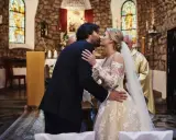 Para młoda całuje się podczas ślubu kościelnego. Panna młoda w pięknej sukni, pan młody w garniturze.