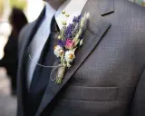 Brat weselny w garniturze, ozdobiony bukiecikiem suszonych kwiatów. Widać, kto jest kim w weselu dzięki jego eleganckiemu wyglądowi.