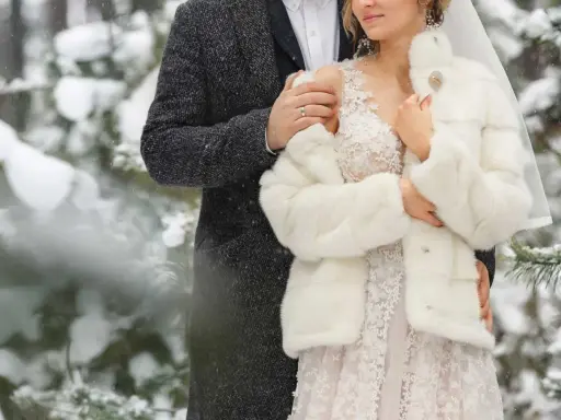 Para młoda w objęciach, otulona śniegiem i miłością. Romantyczne zimowe wesele w lesie.