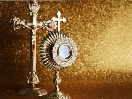 Monstrancja i krzyż na złotym tle. IHS to symbol Jezusa, który jest obecny w Eucharystii.