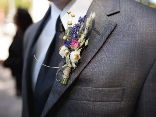 Brat weselny w garniturze, ozdobiony bukiecikiem suszonych kwiatów. Widać, kto jest kim w weselu dzięki jego eleganckiemu wyglądowi.